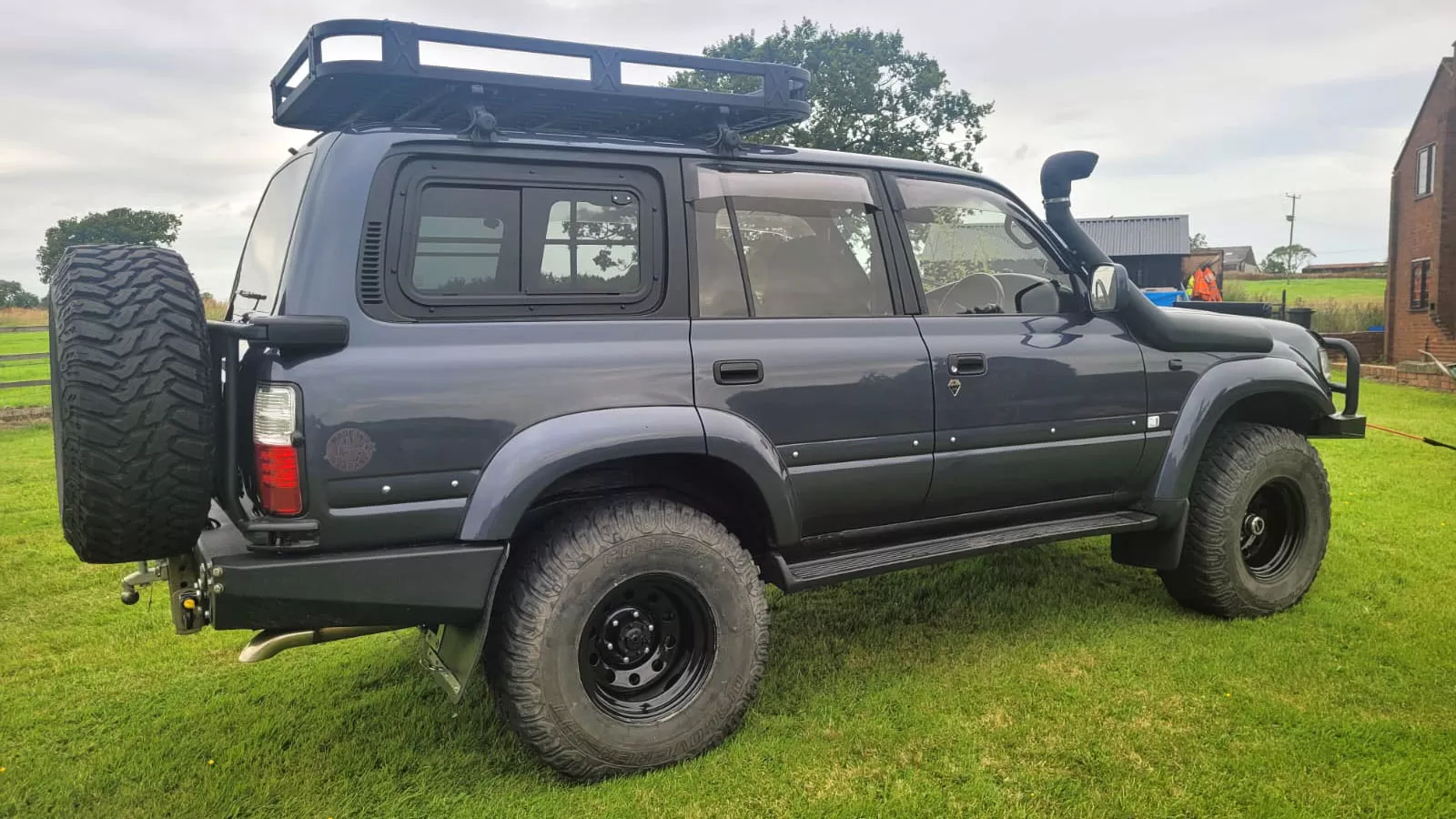 Toyota Land Cruiser 80 featuring an Explore Glazing sliding window, showcasing the rear and side view on a grassy area.